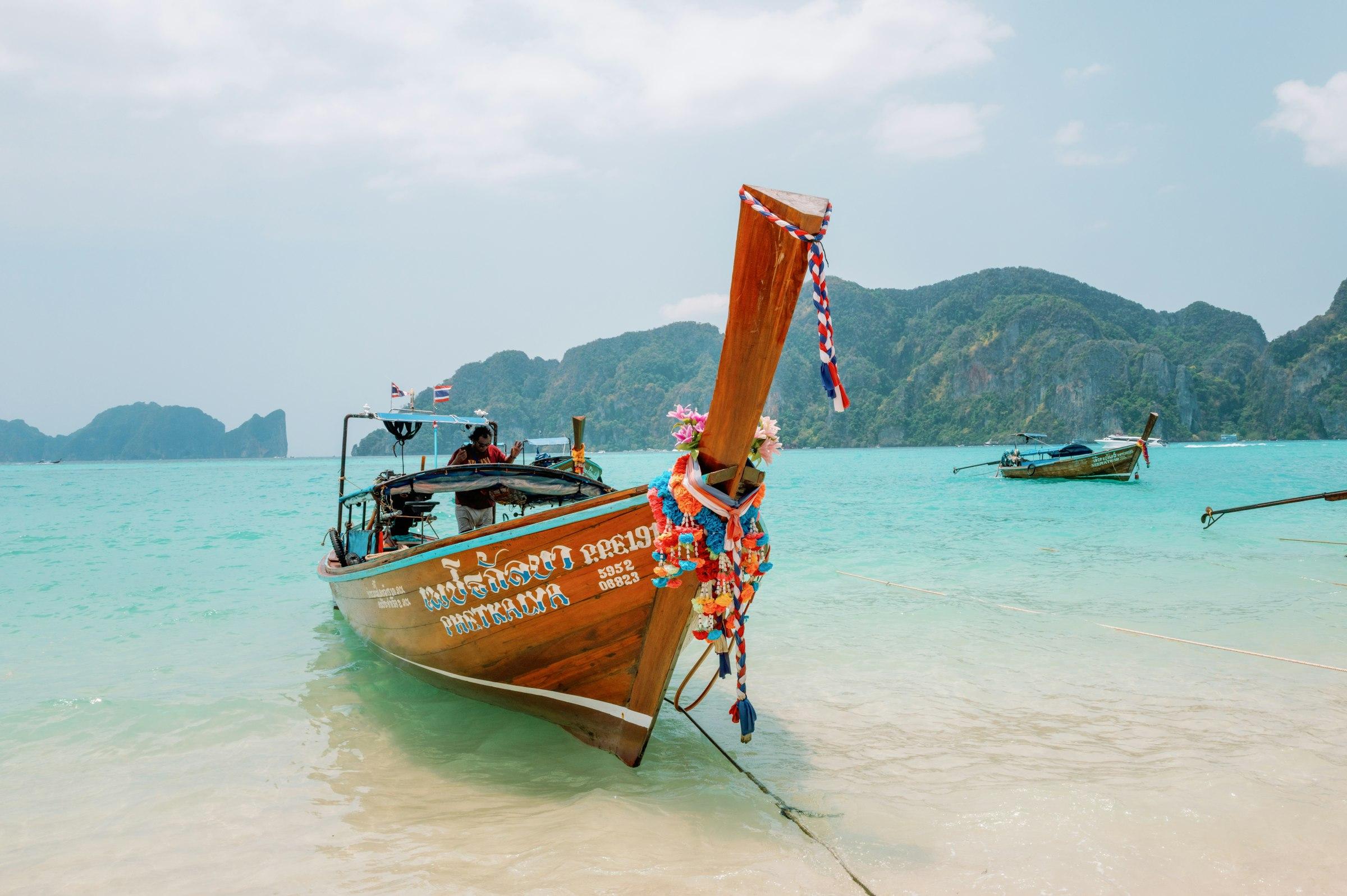 A decorated Thai longtail boat beached bow-first on Phi Phi with limestone hills behind