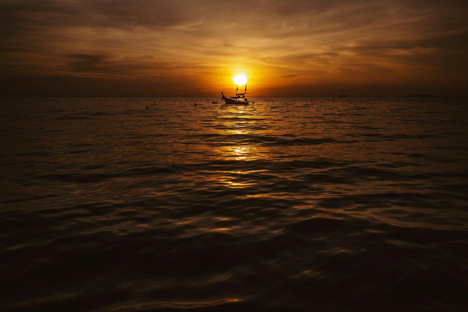 Silhouette of a longtail boat on the water at sunset